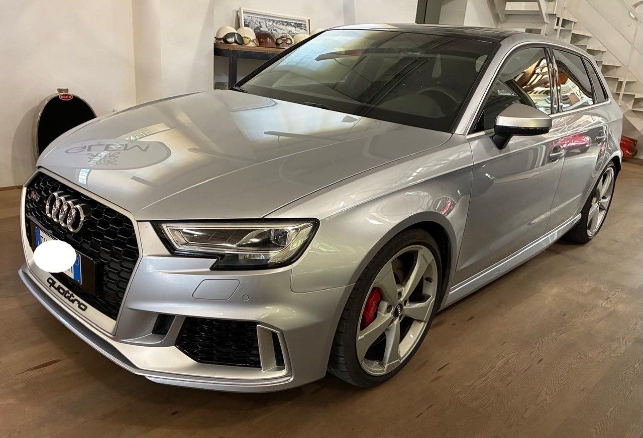 Berlina Audi color argento parcheggiata al chiuso, vista frontale di tre quarti con griglia nera e pinze dei freni rosse.