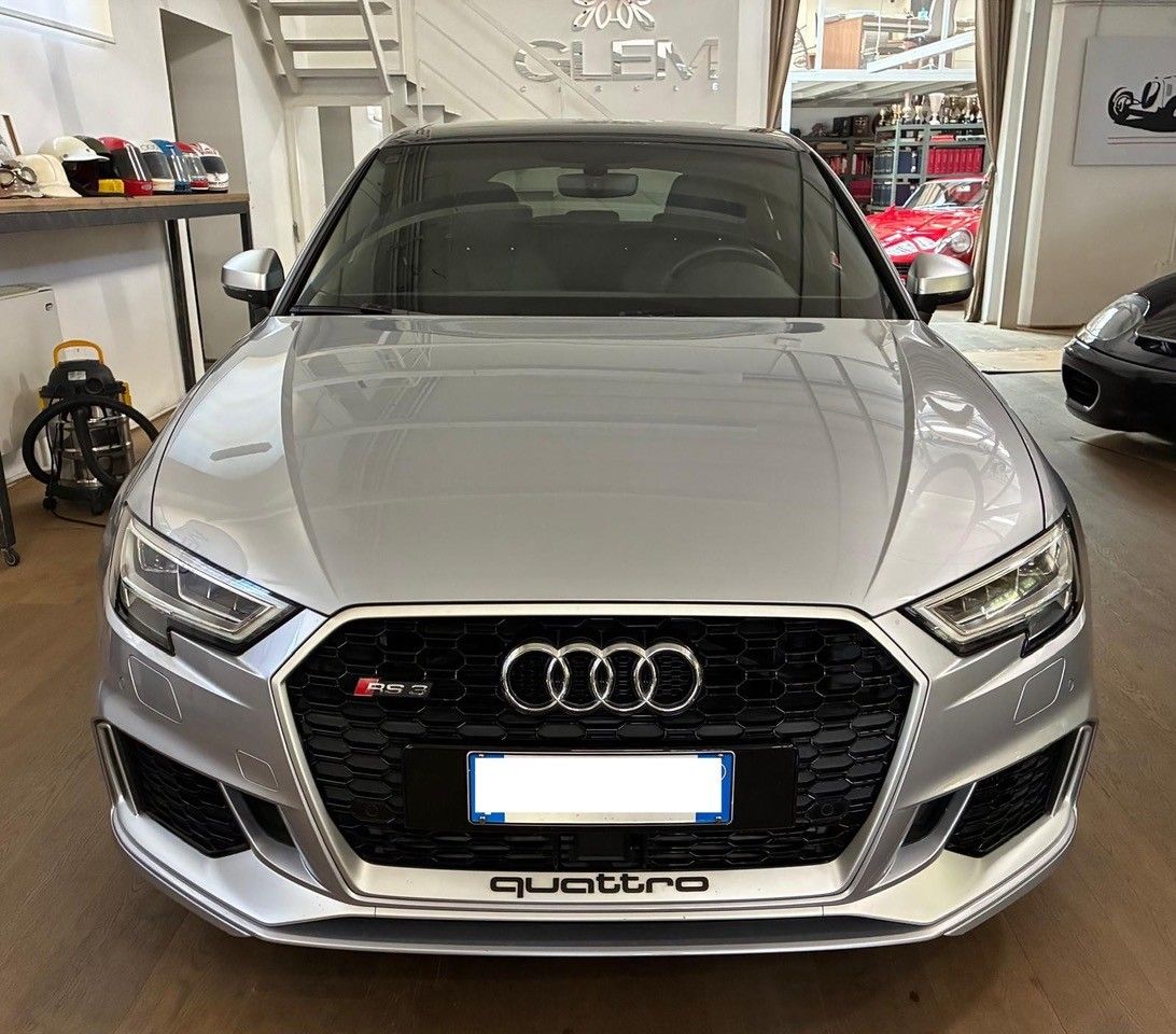 Vista frontale di una berlina Audi color argento in uno showroom, con griglia nera e stemma rosso.