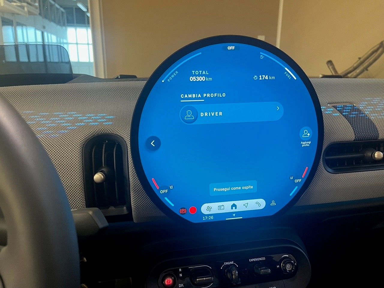 Cruscotto dell'auto con display digitale rotondo blu che mostra la navigazione e i comandi del veicolo.