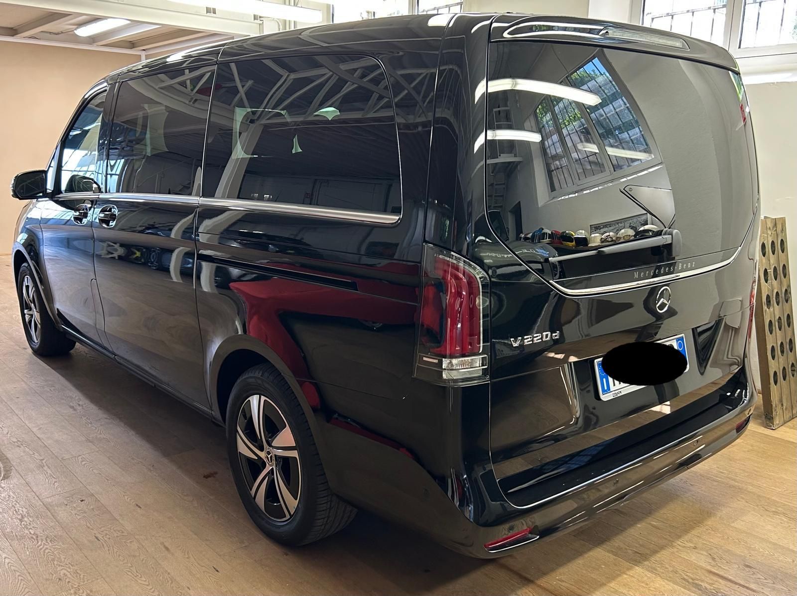 Un furgone passeggeri Mercedes-Benz Classe V nero parcheggiato all'interno di uno showroom con pavimento in legno.