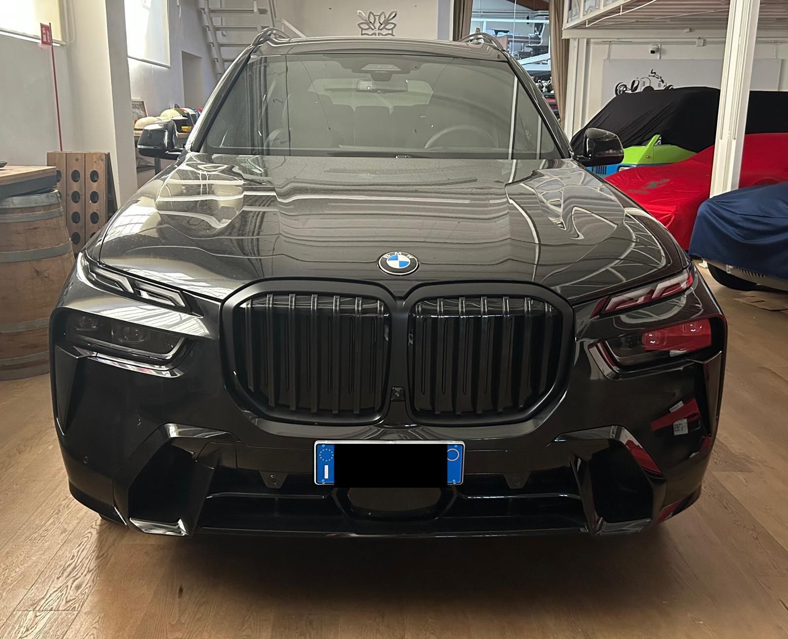 Un SUV BMW grigio scuro parcheggiato in un garage, rivolto in avanti.