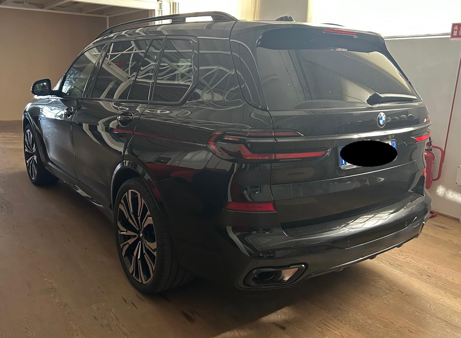 Un SUV BMW nero parcheggiato all'interno, visto da una prospettiva di tre quarti posteriore.