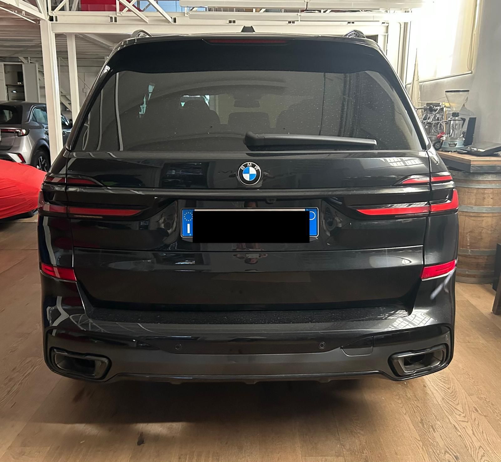 Vista posteriore di un SUV BMW nero parcheggiato all'interno di un garage su un pavimento in legno.