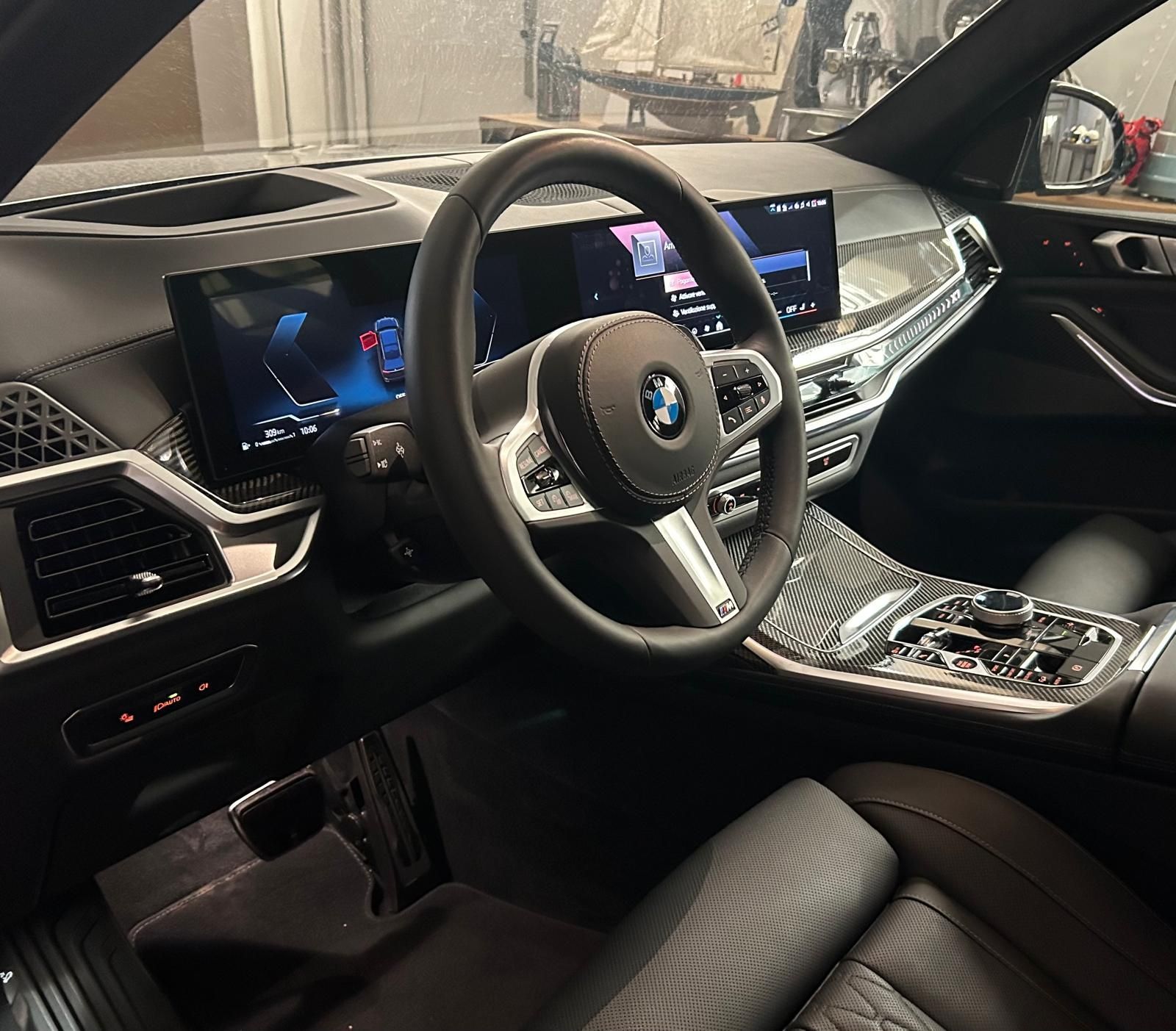 Gli interni di una BMW, che mostrano un cruscotto elegante con un ampio display curvo, volante in pelle nera e sedili.