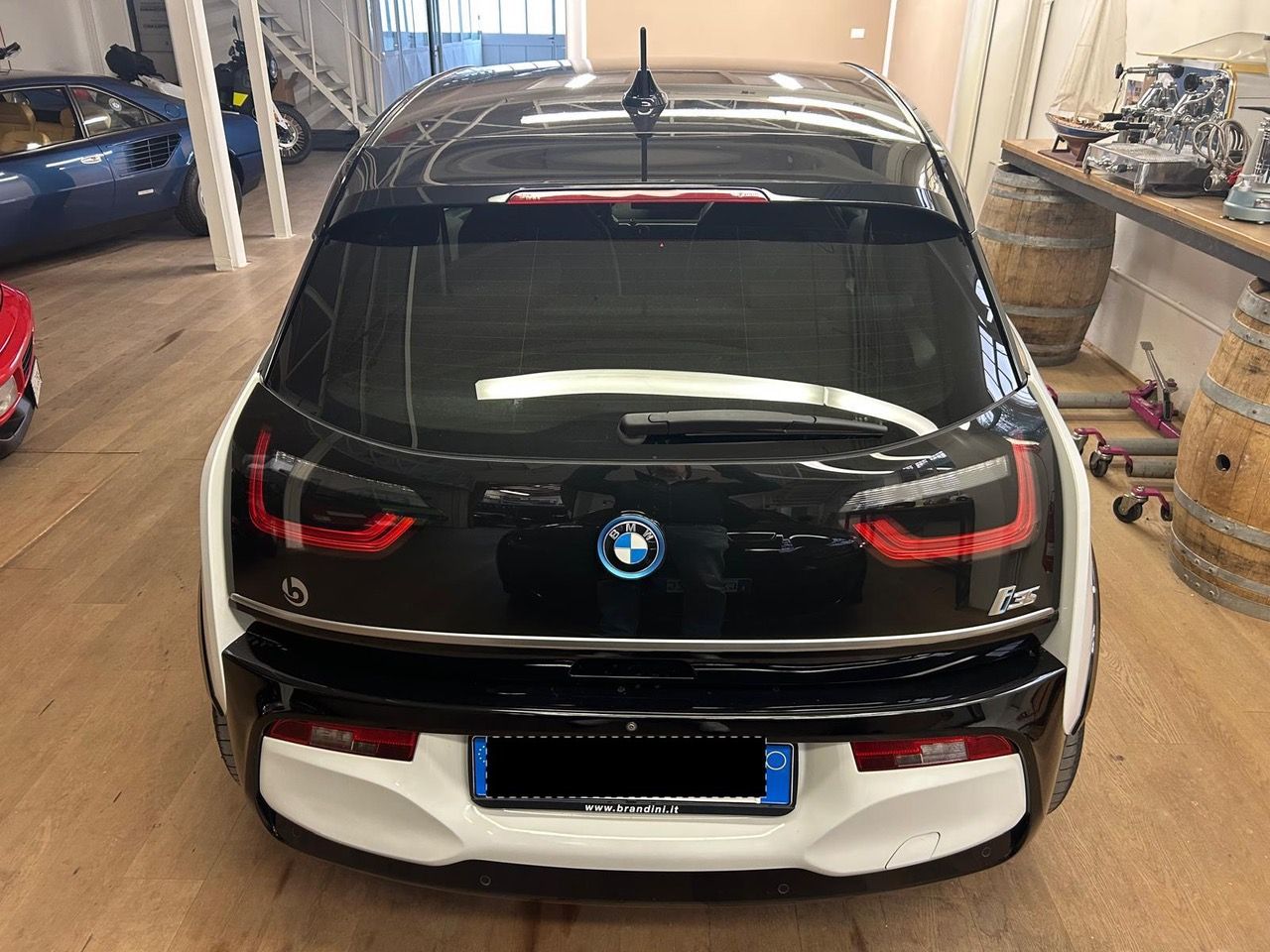 Vista posteriore di una BMW i3 hatchback bianca e nera parcheggiata all'interno di un garage.