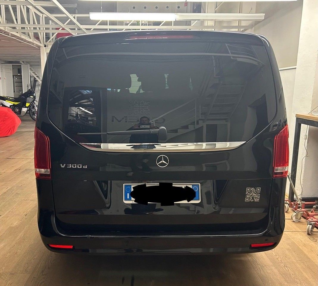 Vista posteriore di un furgone Mercedes-Benz Classe V nero parcheggiato all'interno di un'officina o di un garage.