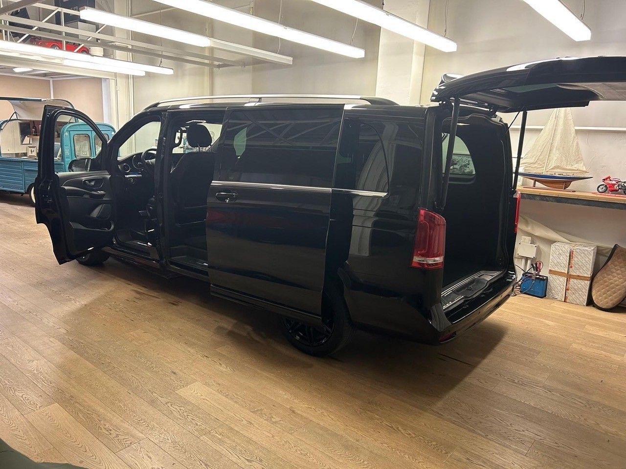 Un furgone nero con le portiere e il portellone posteriore aperti, parcheggiato all'interno di uno showroom o di un'officina ben illuminata.