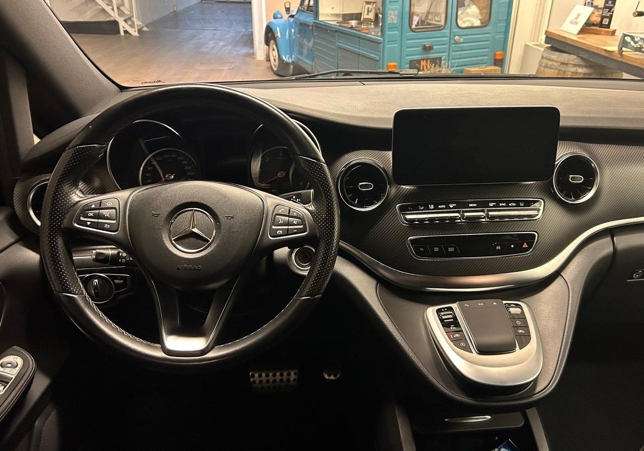Interni di un furgone Mercedes-Benz nero, con particolare attenzione al volante, al cruscotto e al display digitale.