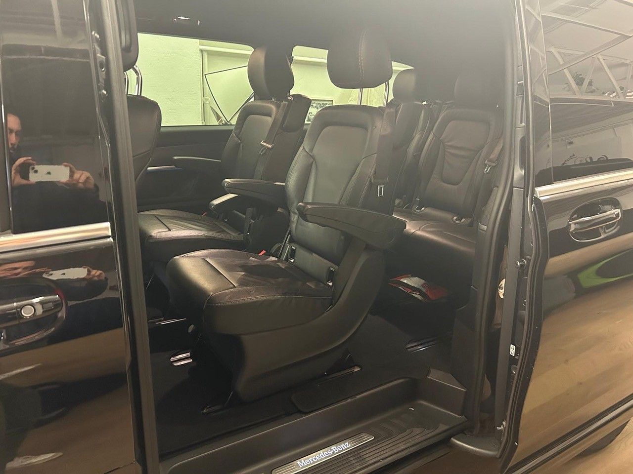 Sedili in pelle nera all'interno di un furgone di lusso, con una porta laterale aperta e la configurazione dell'abitacolo.
