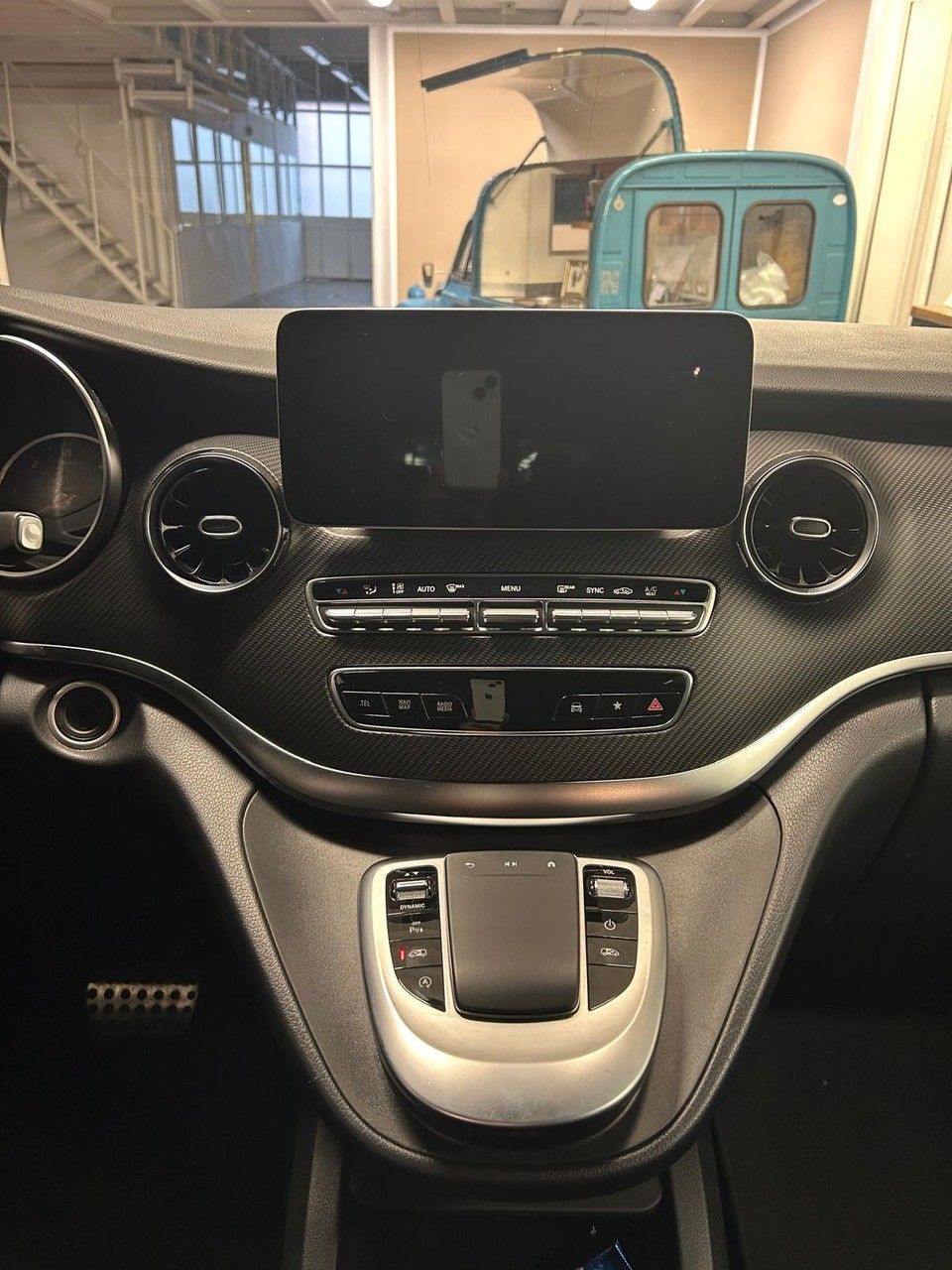 Il cruscotto interno di un furgone Mercedes-Benz con touchscreen centrale, bocchette d'aria circolari e trackpad.
