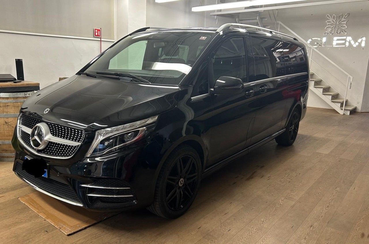 Un minivan Mercedes-Benz Classe V nero parcheggiato all'interno di un'officina, con una scala sullo sfondo.