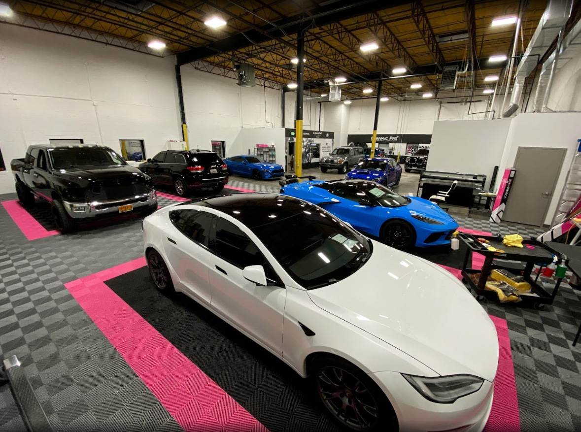 a white tesla model s is parked in a garage with other cars .