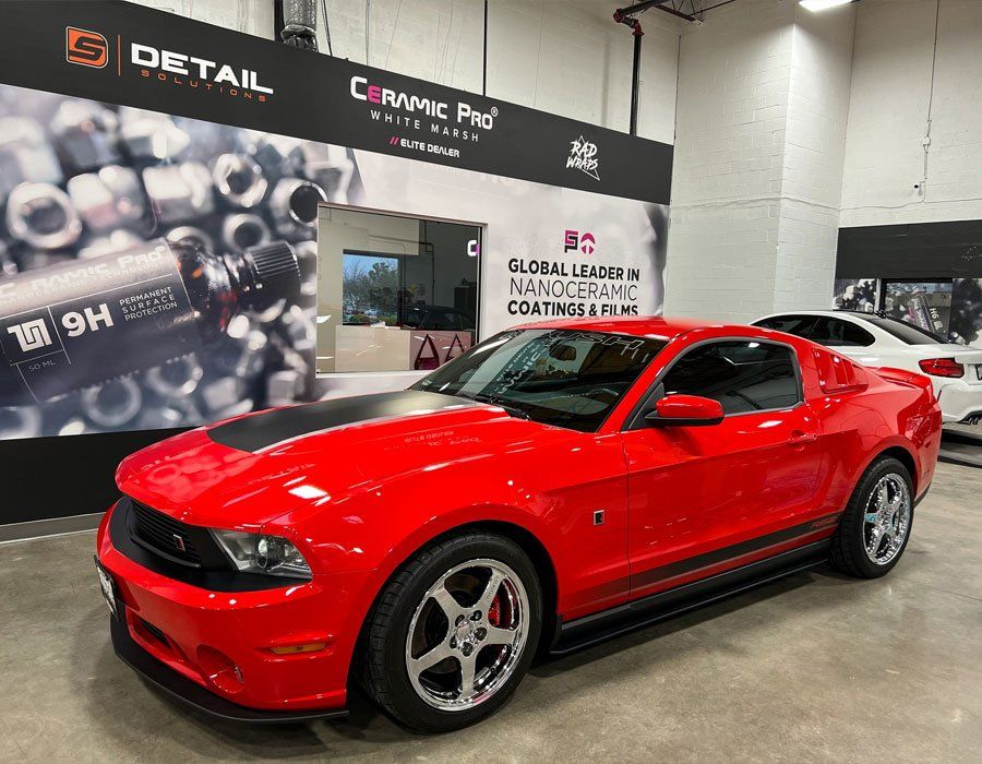 A red ford mustang is parked in a showroom.