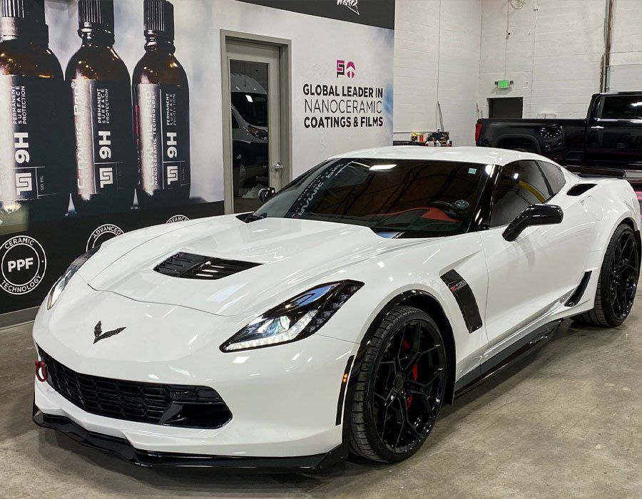 A white corvette zr1 is parked in a showroom.