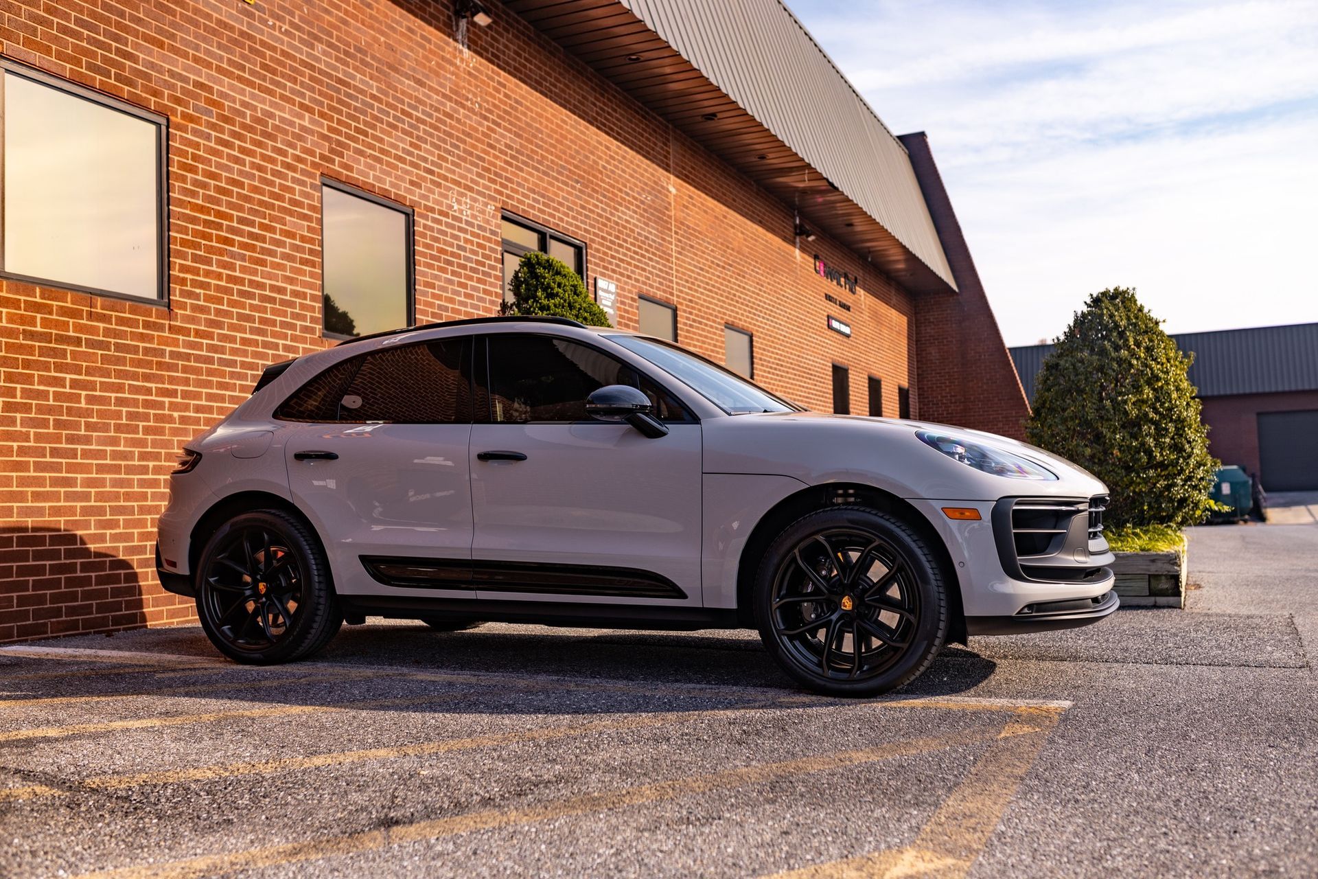 Silver SUV parked beside a brick building at sunset