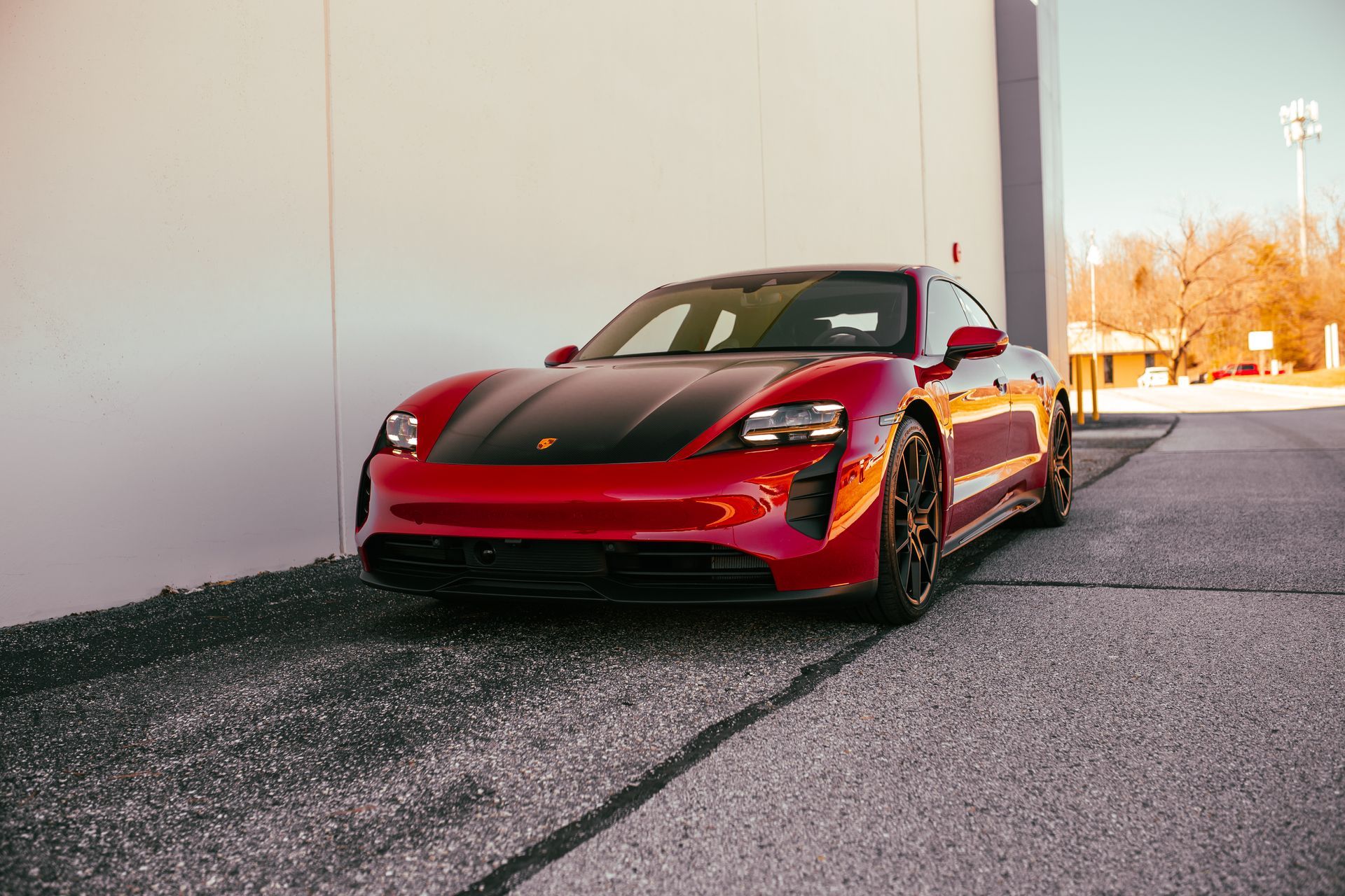 A red porsche taycan is parked in front of a building.