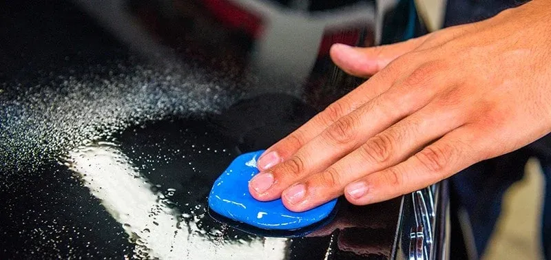 a person is using blue clay to clean a car .
