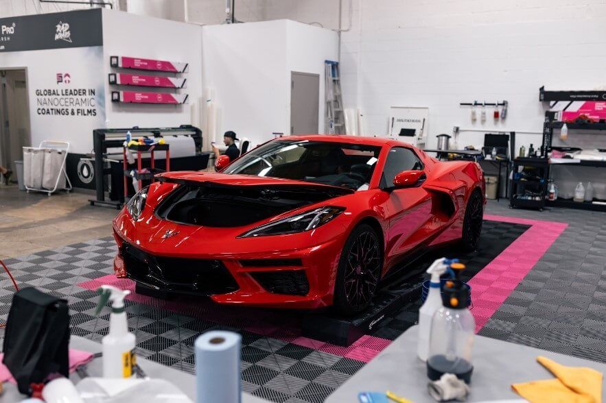 A red corvette is parked in a garage with its hood open.