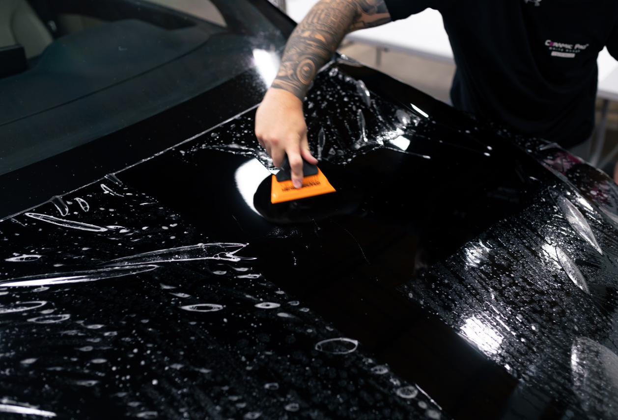 A man is cleaning a black car with a sponge.