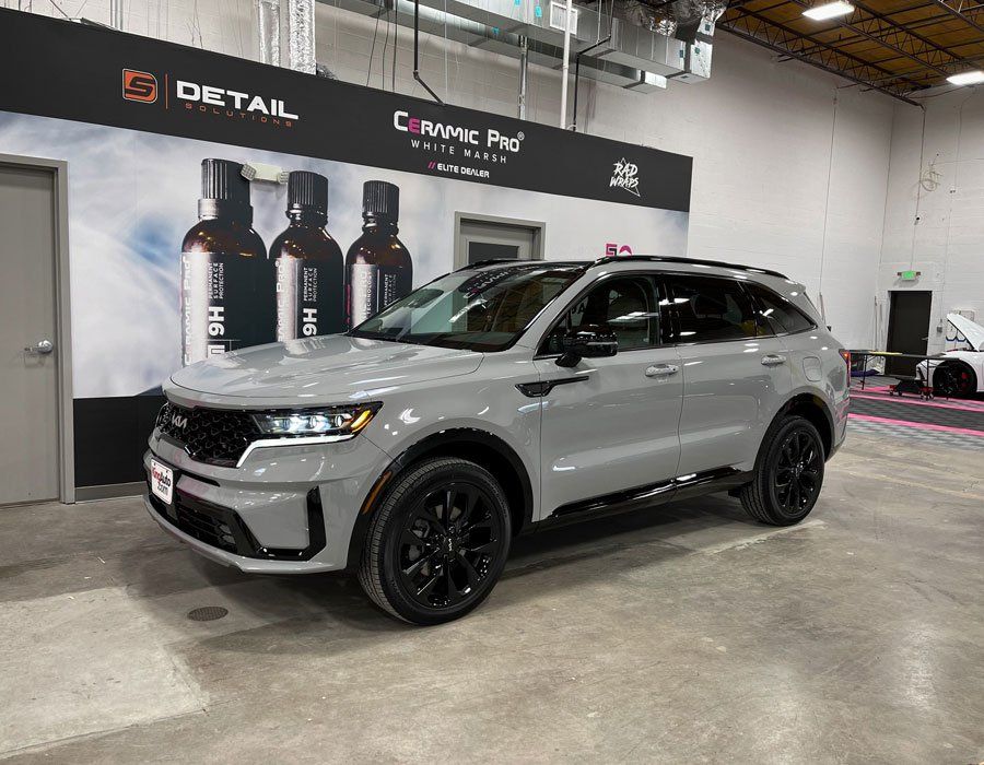 A gray suv is parked in a garage next to a wall with bottles on it.