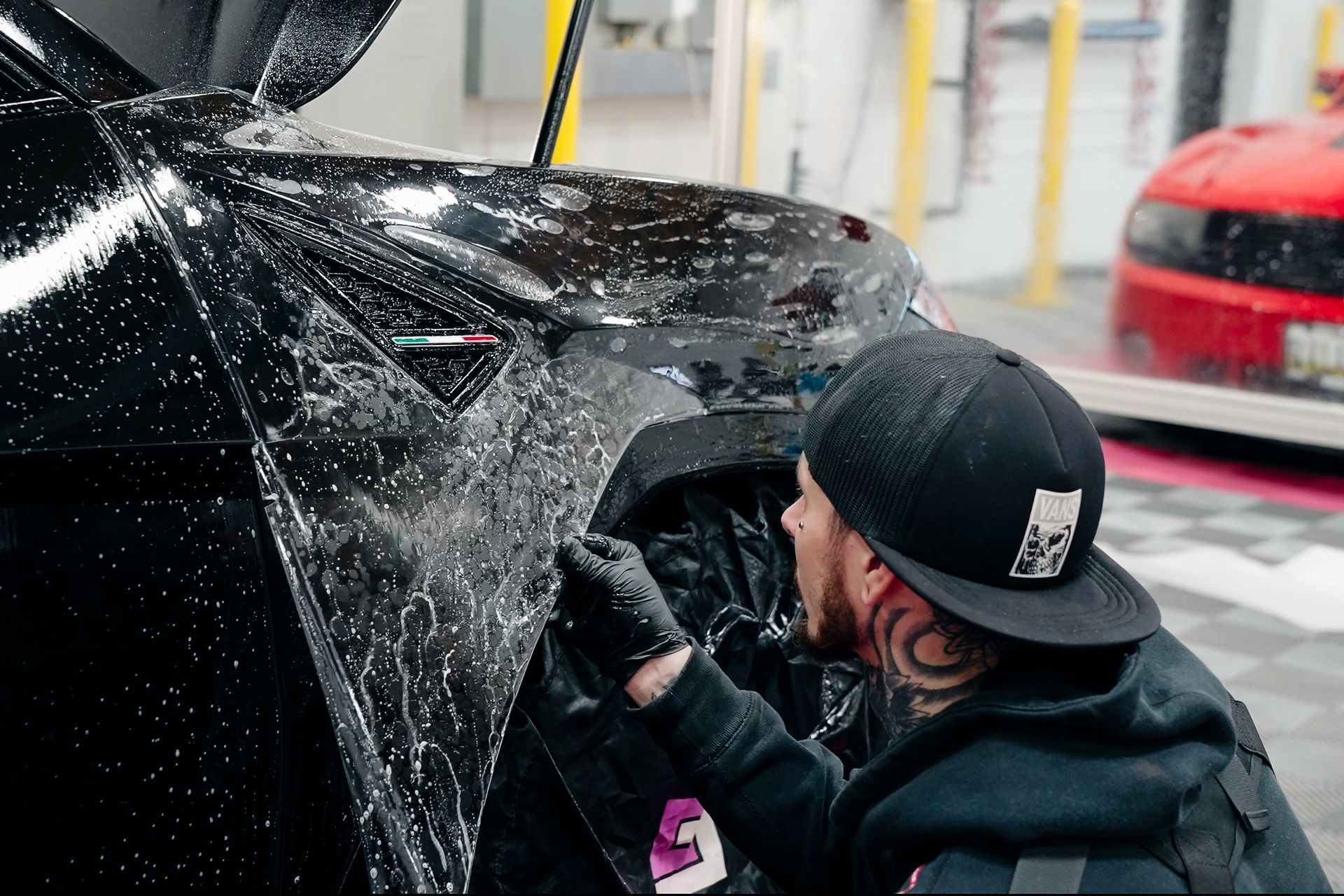 A man is wrapping a black car with a black wrap.