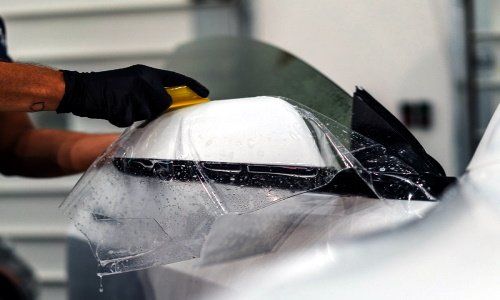 a person is wrapping a car with plastic wrap .
