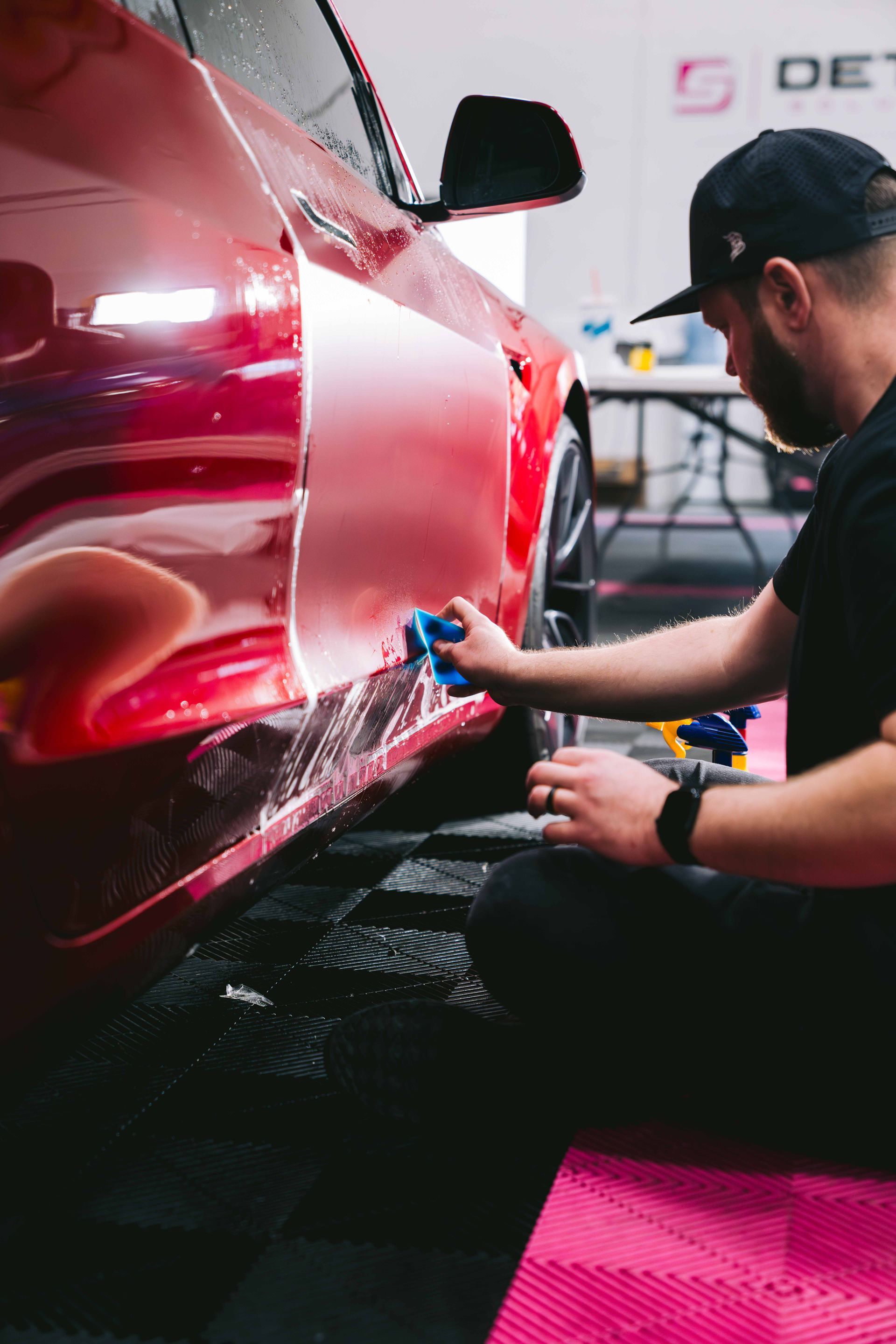 Mechanic polishing a red car in a workshop with a blue cloth