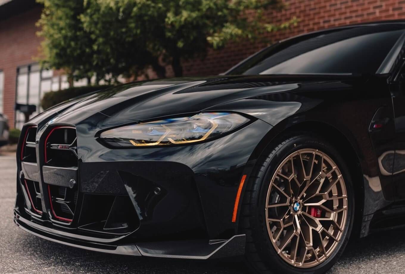 A black bmw m4 is parked in front of a brick building.