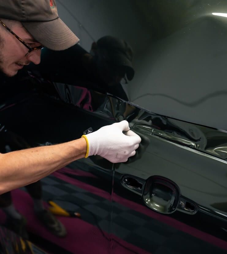 A man wearing white gloves is working on a car
