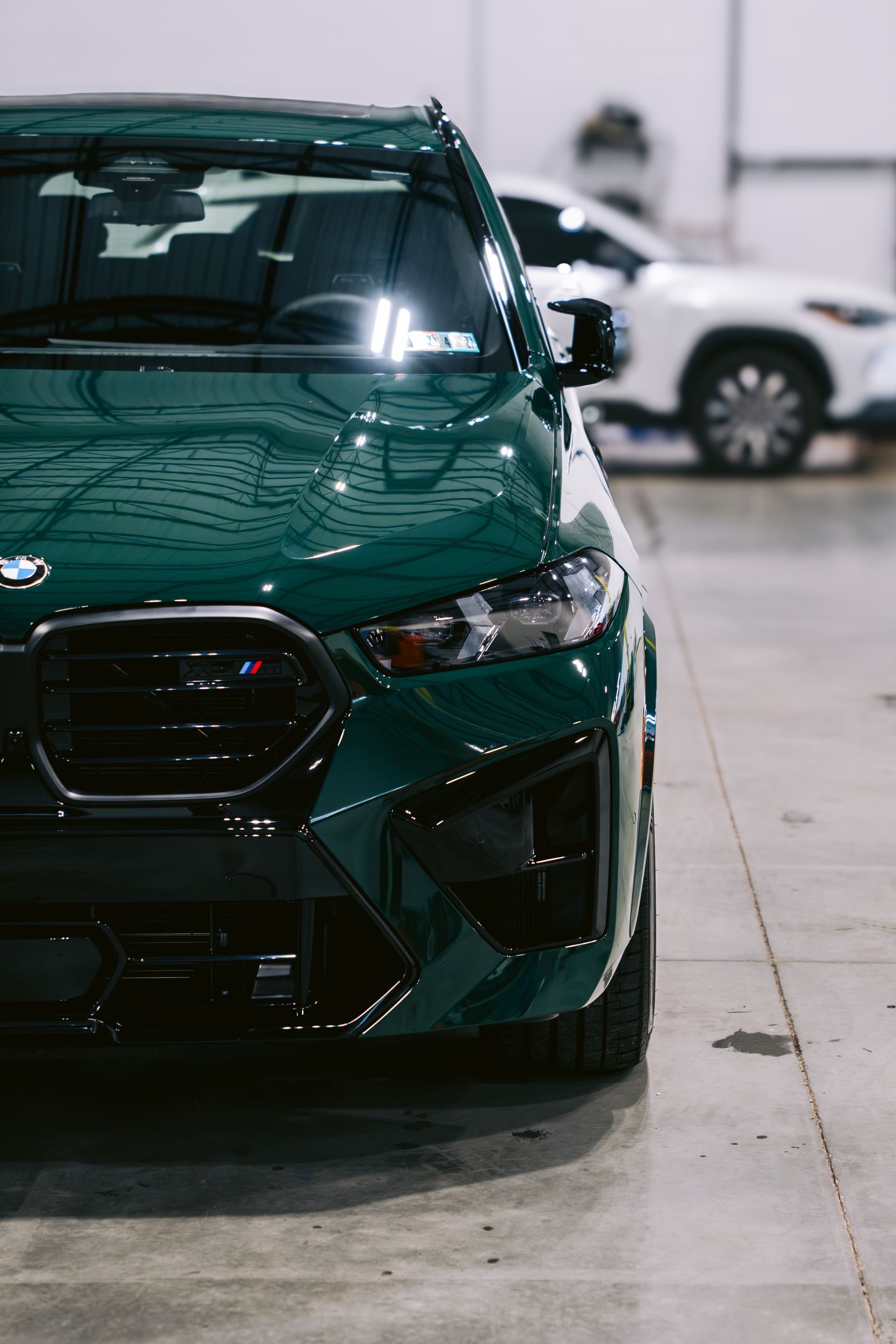 Front view of a dark green sports car parked indoors on a concrete floor