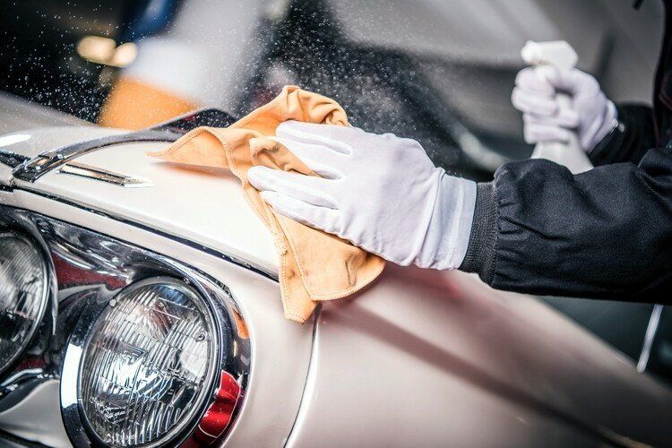 A person is cleaning a car with a cloth and spray bottle.