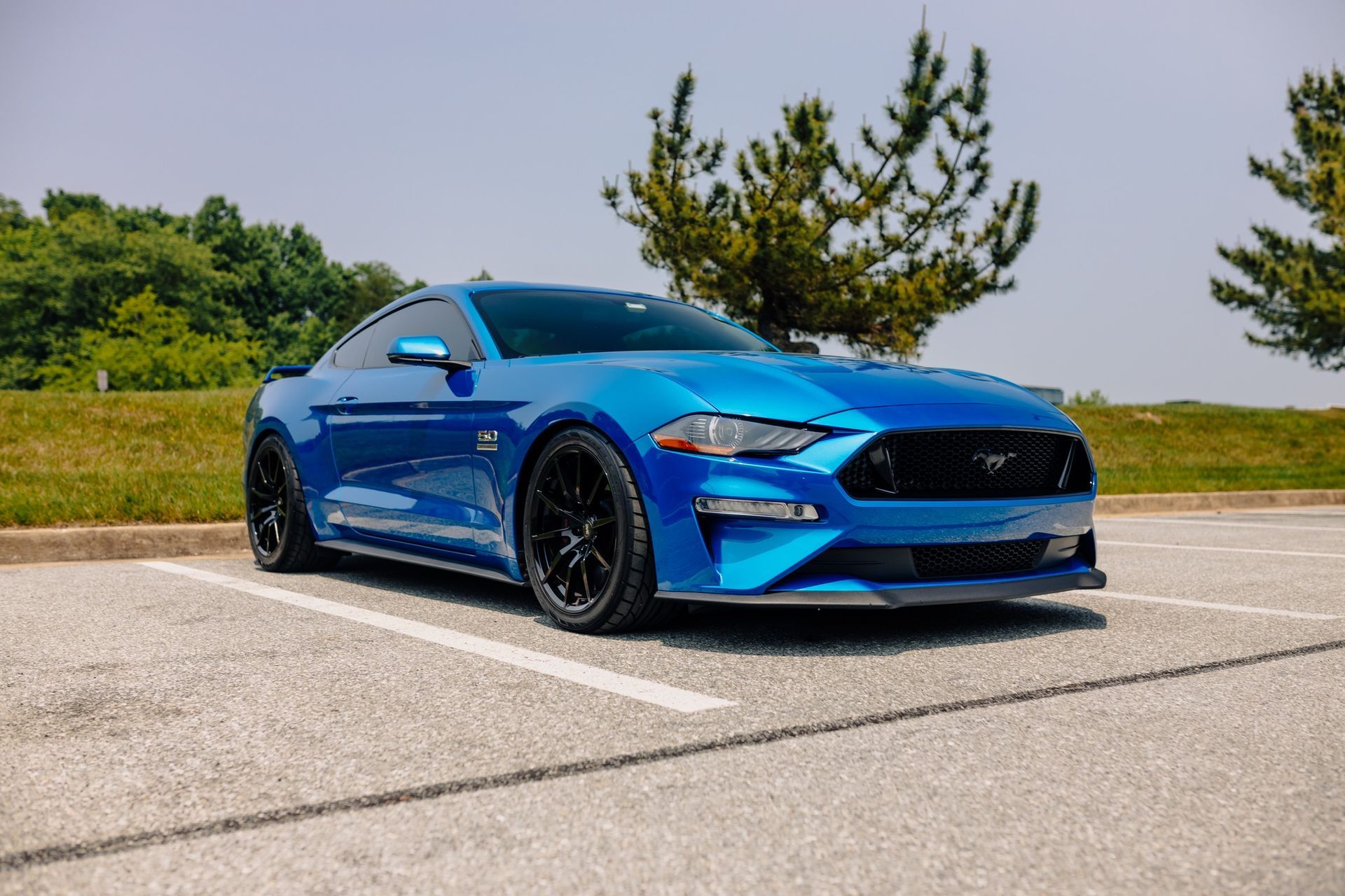 A blue ford mustang is parked in a parking lot.