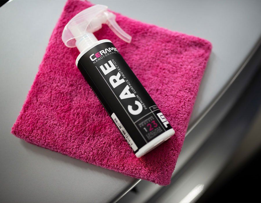 A bottle of care is sitting on a pink towel