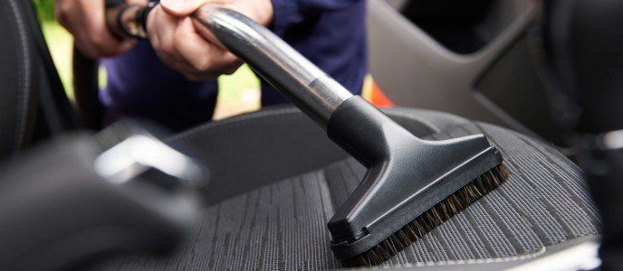 a person is cleaning the seats of a car with a vacuum cleaner .