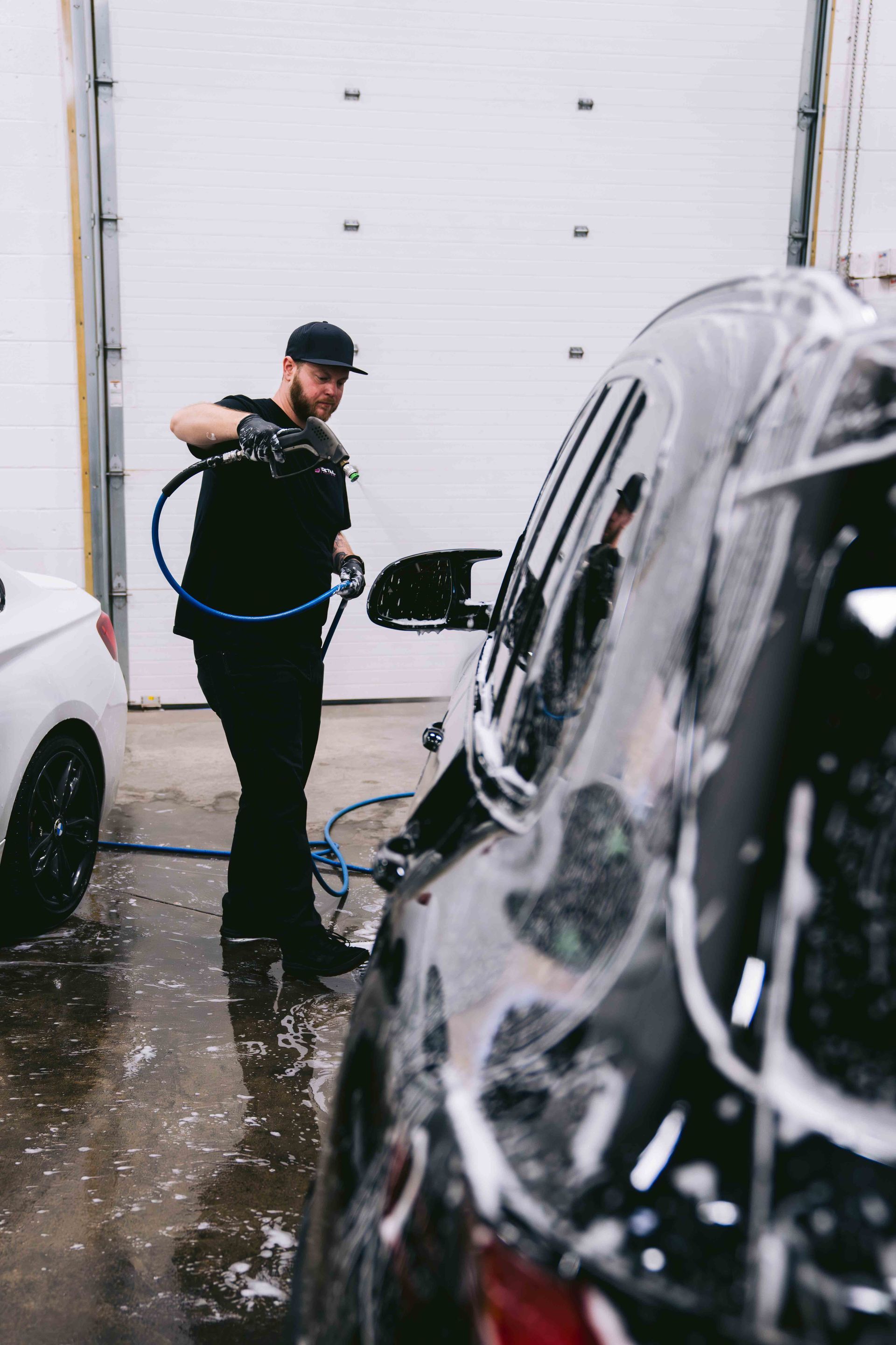 A man is washing a car with a hose.