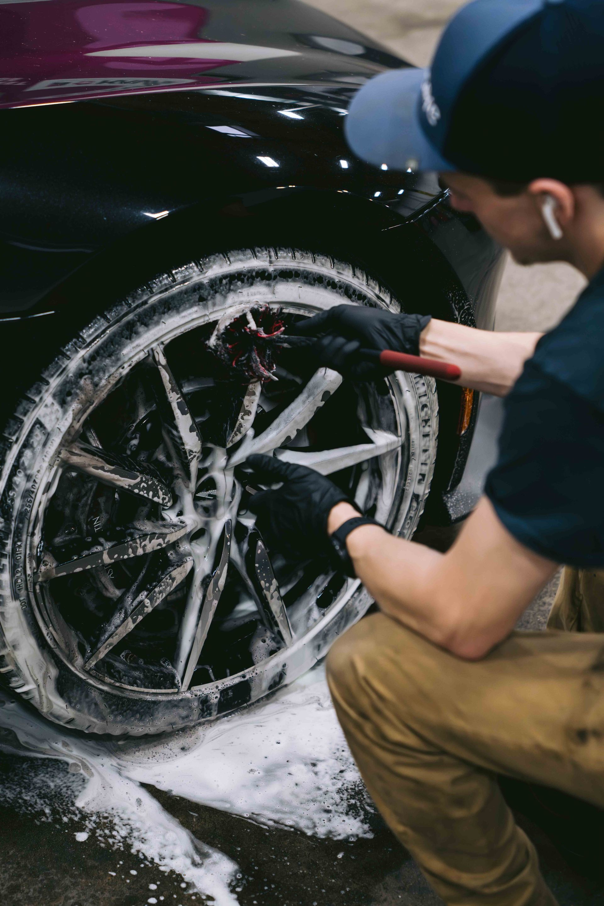 A man is cleaning a car wheel with soap and water.