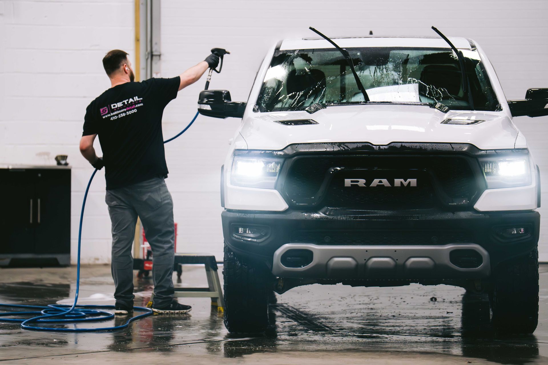 A man is washing a white ram truck in a garage.