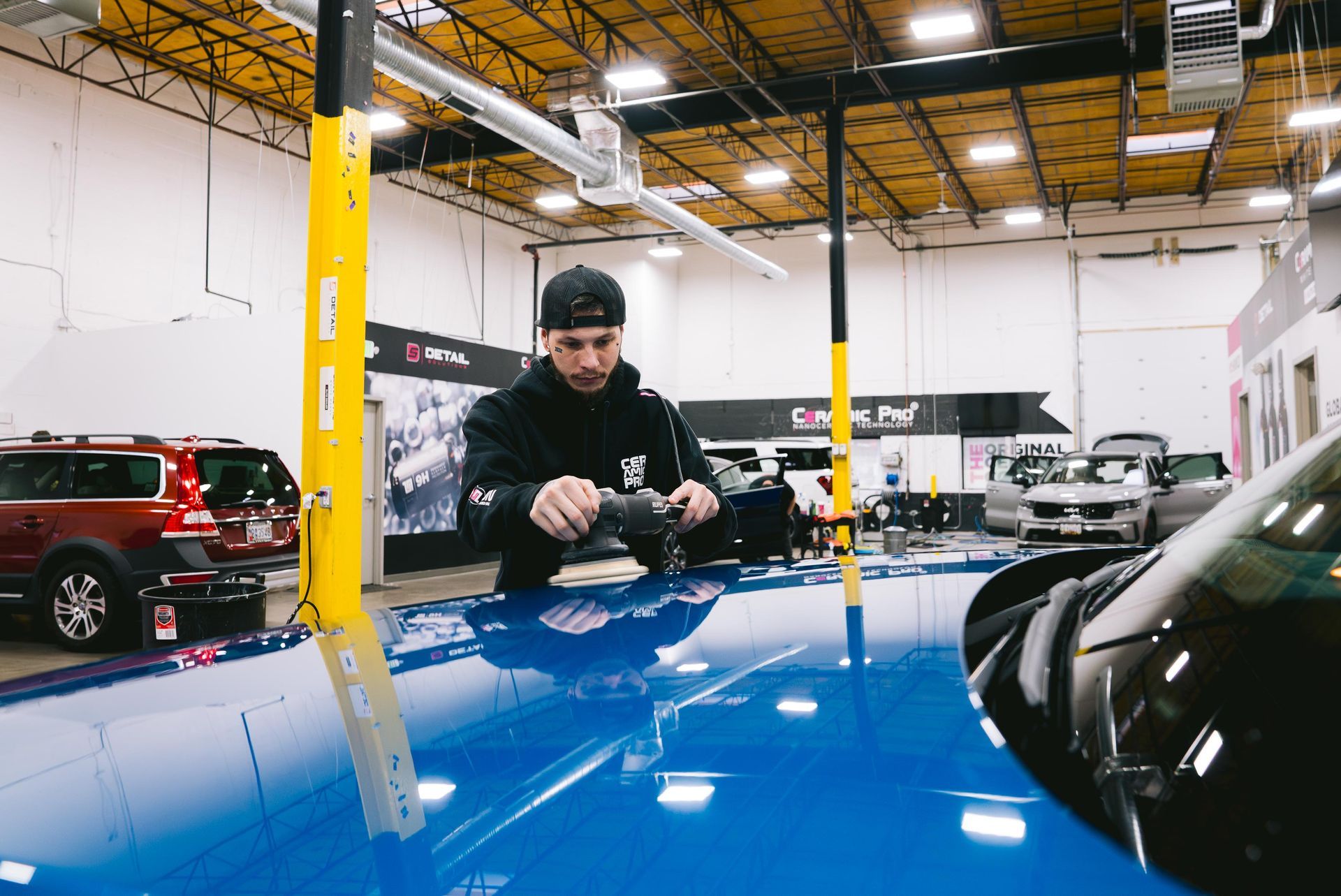A man is polishing a blue car in a garage.