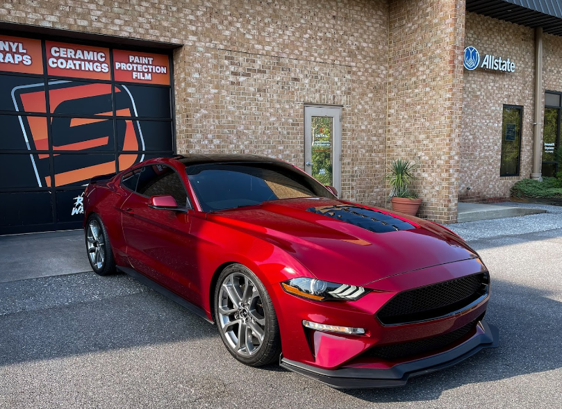 a red mustang is parked in front of a brick building .