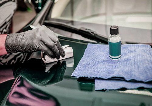 A person is polishing the hood of a car.