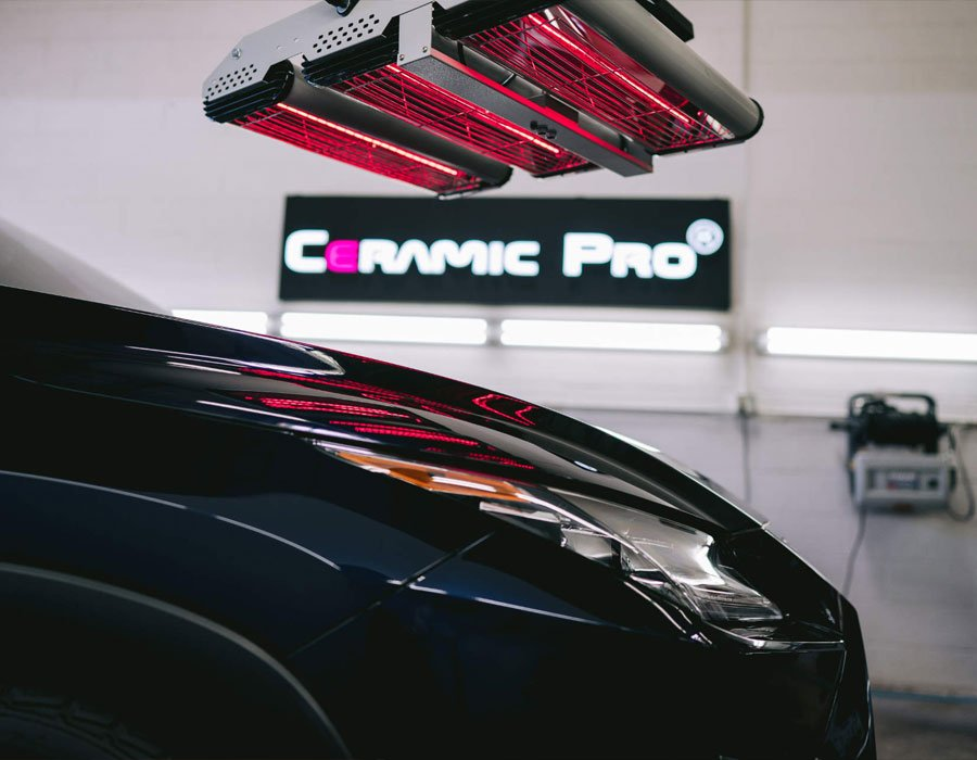 A car is sitting under a ceramic pro sign