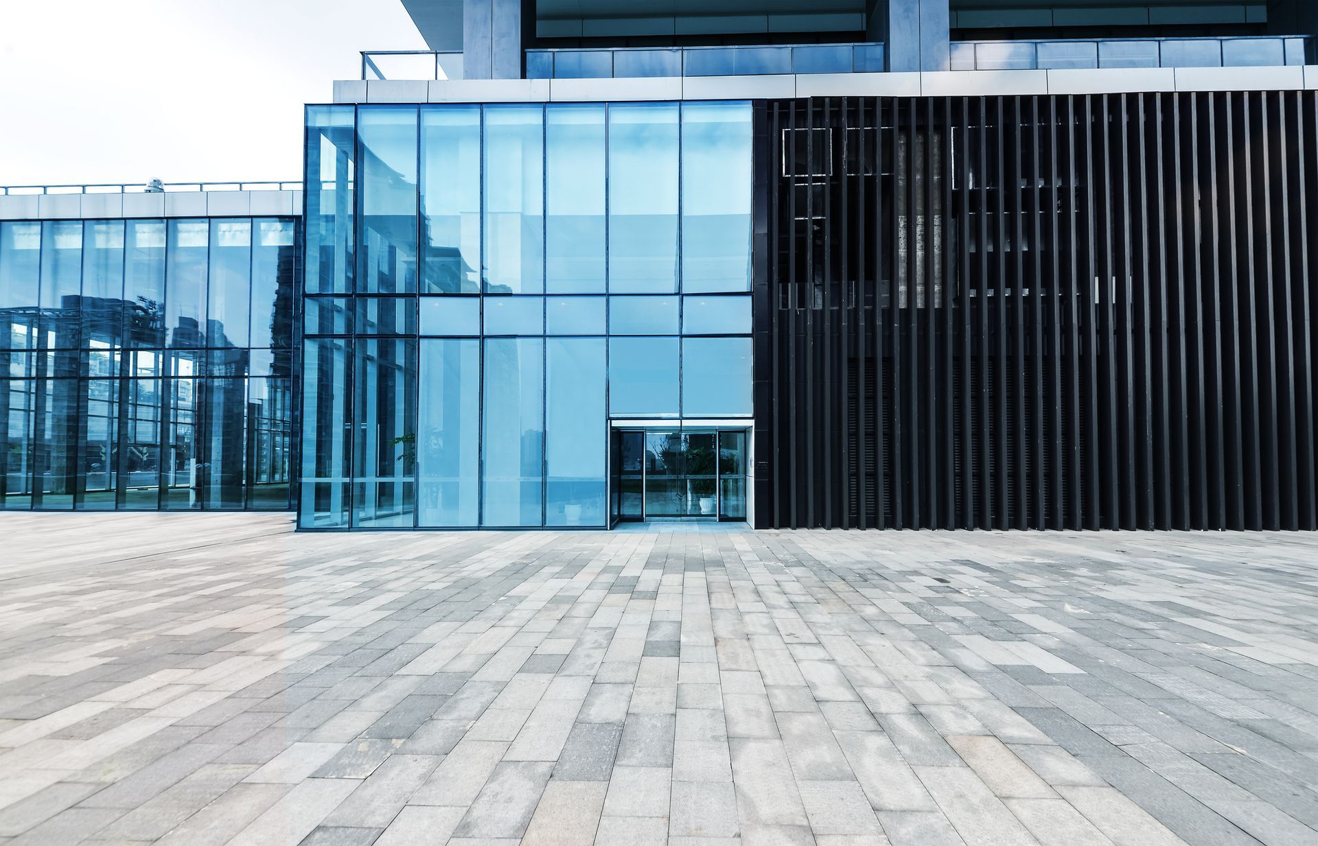 A large building with a lot of windows and a brick walkway in front of it .