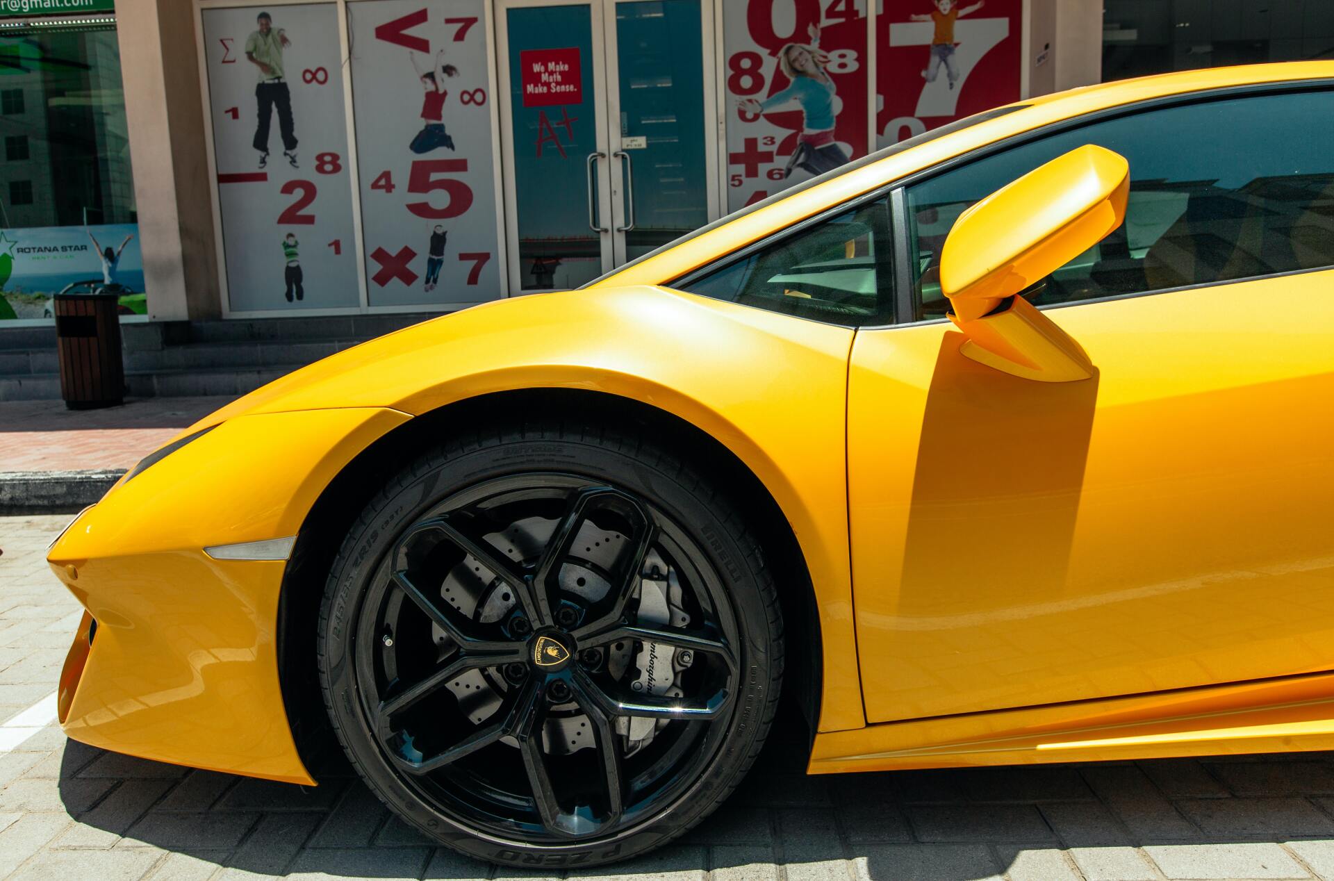 A yellow sports car is parked in front of a store