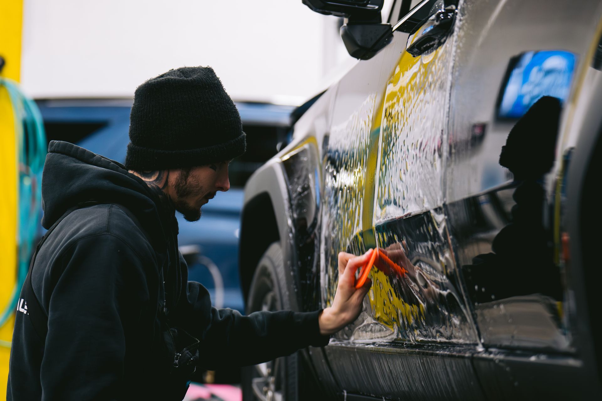 Technician applying paint protection film on black truck for scratch and chip protection