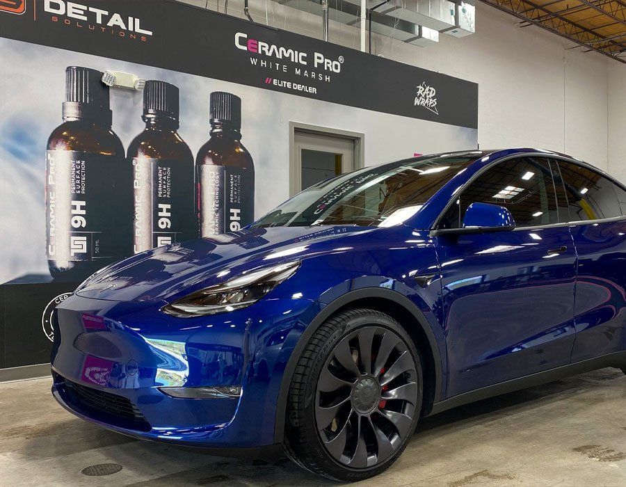 A blue tesla model y is parked in a garage.