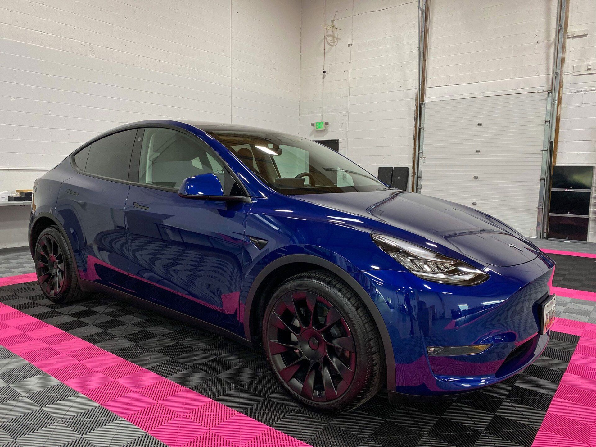 A blue tesla model y is parked in a garage.