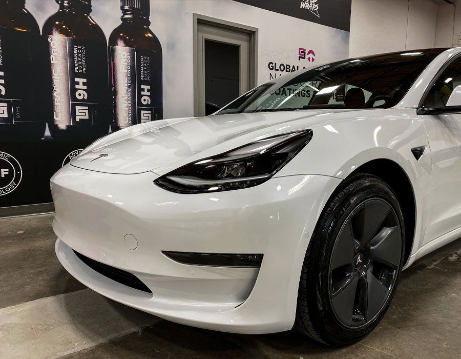 A white tesla model 3 is parked in a garage.