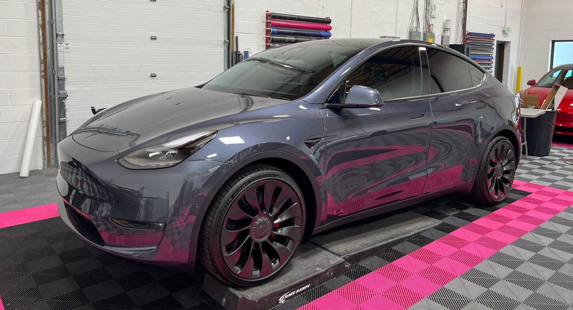 A tesla model y is parked in a garage.