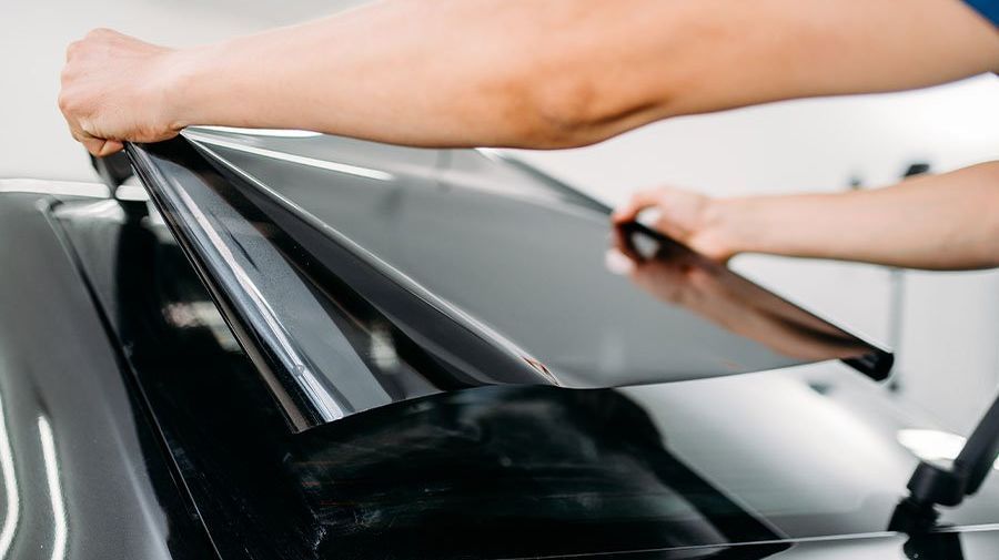 A person is applying tinted glass to a car window.