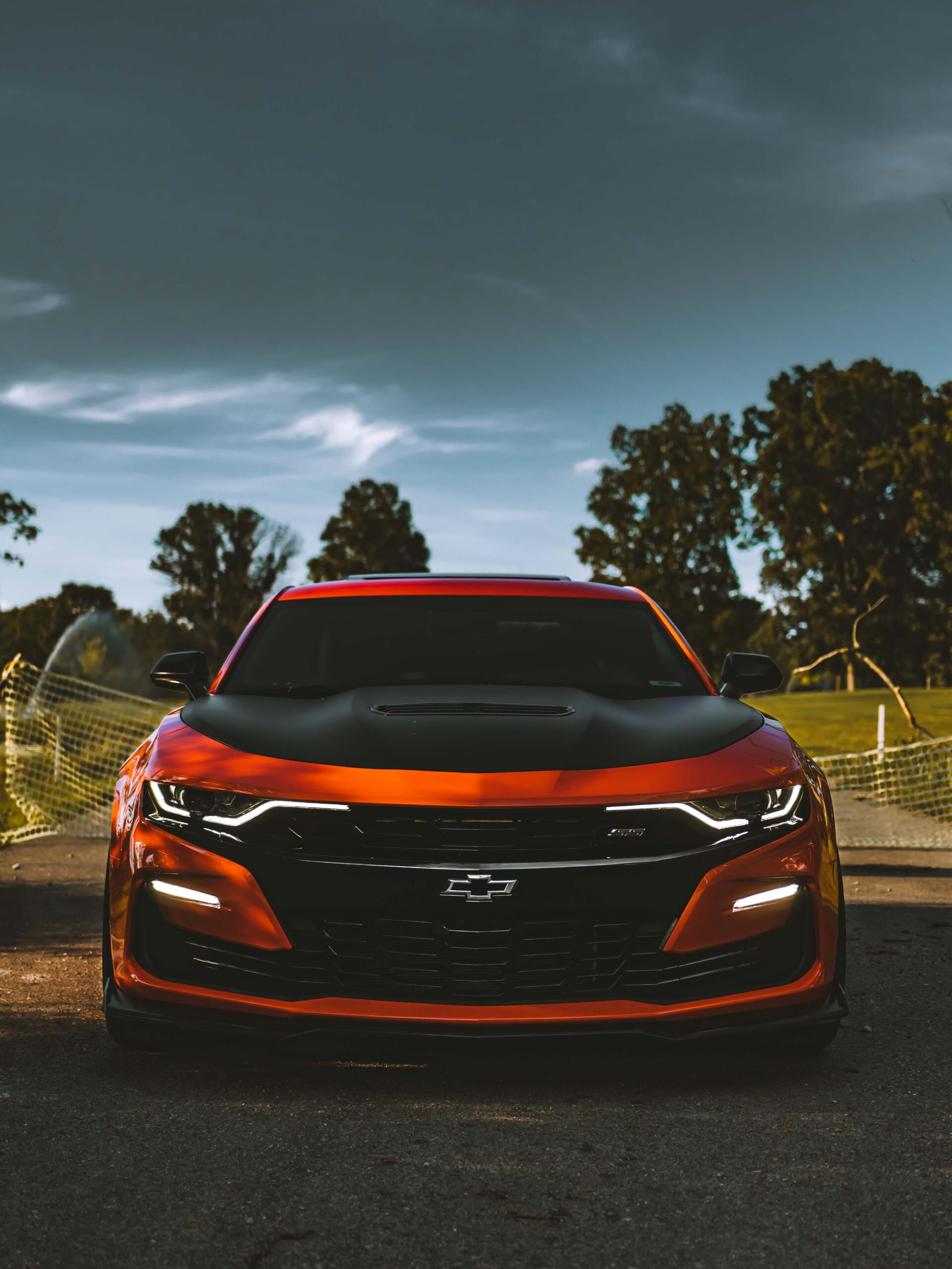 A red chevrolet camaro is parked on the side of the road